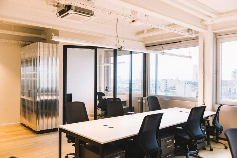 Wide-angle view of the modern office at Italielei 124 featuring shared desks and large windows.