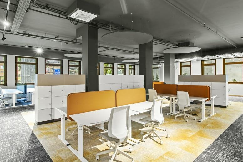 Spacious open-plan workspace at Kelsenstraße 5, Wien, Austria with modern white desks and yellow privacy screens.