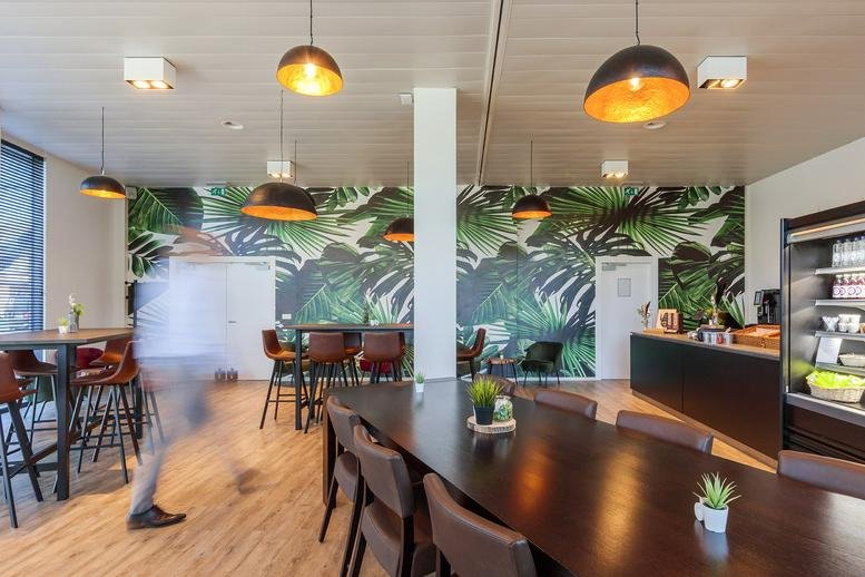 Spacious communal dining area with a tropical plant wall and designer pendant lighting at Korte Keppestraat 19-21-23.