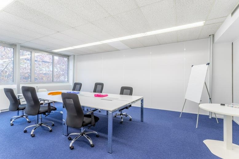 Spacious meeting room at Le Britannia with white table, ergonomic chairs, and large whiteboard.