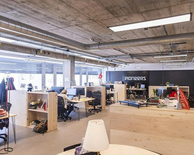 Spacious open-plan workspace at Liechtensteinstraße 111-115 with industrial concrete ceilings and wooden storage units.