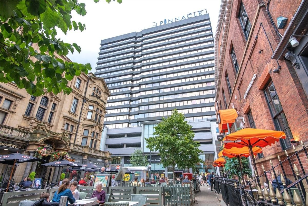 Exterior view of the Pinnacle at 67 Albion Street showing the tall skyscraper and street-level cafes.