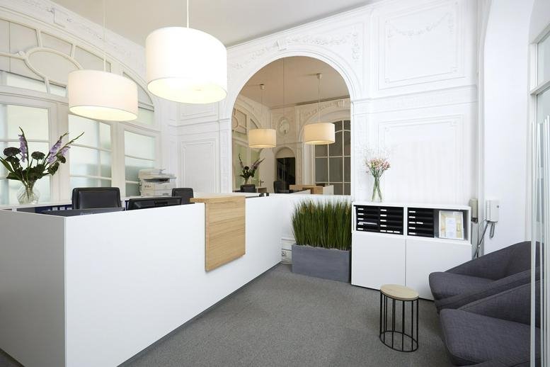 Reception area at Rue Abbé Cuypers 3 featuring a white desk, arched doorway, and modern pendant lights.