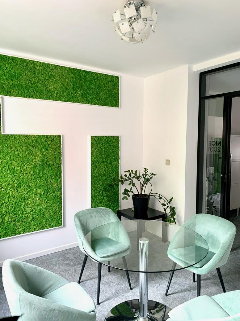 Communal dining area at Rue d’Arlon 25 with moss feature walls and light green velvet chairs.