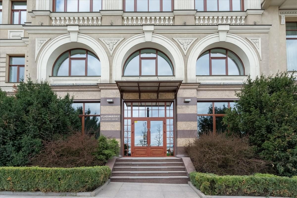 Exterior entrance of the Sagaidachnogo 11 building with arched windows and manicured greenery.