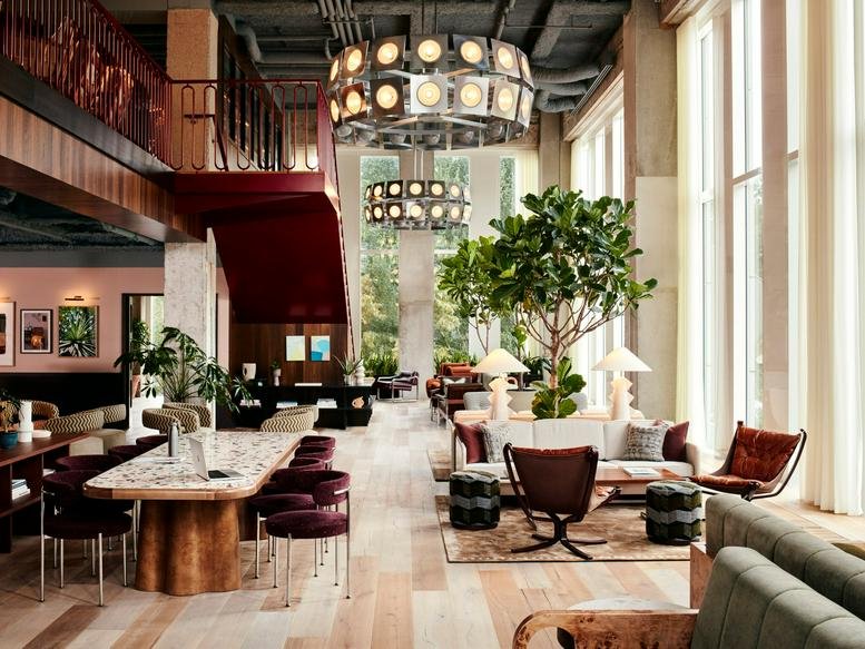 Grand, high-ceilinged communal lounge at Square Victoria Régina 1, Brussels with a feature staircase and large windows.