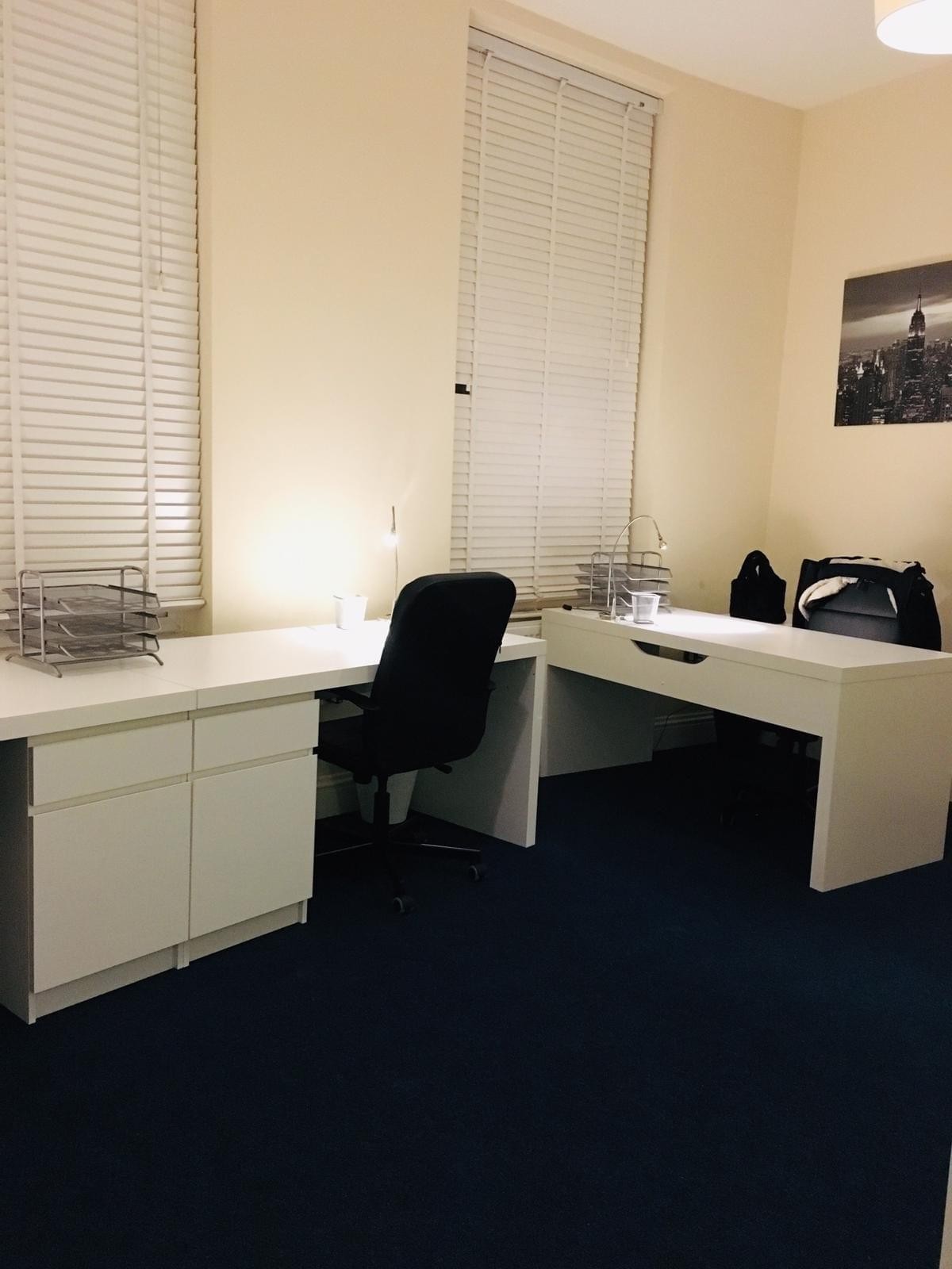 Spacious two-person office suite at 102 Blundell Street with dual white desks and blue carpet.
