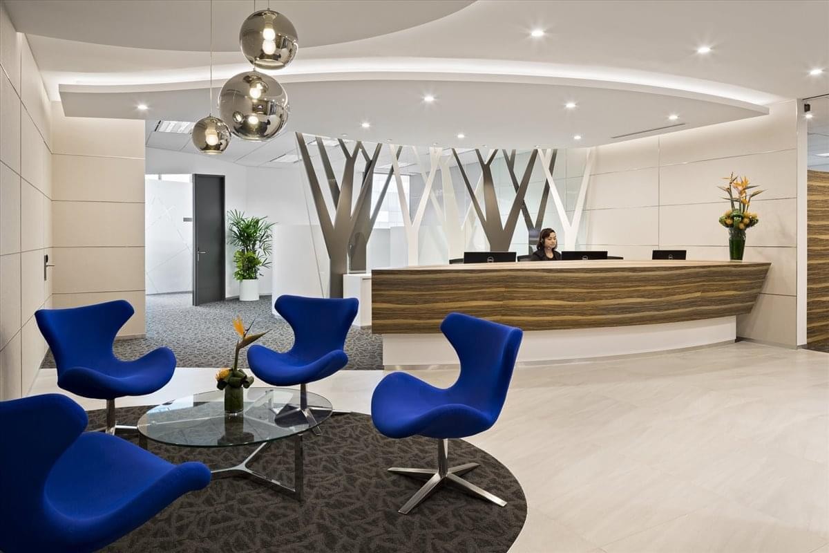 Modern reception lobby featuring bright blue chairs, a wooden desk, and tree-like architectural accents.