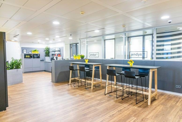 Bright, open-plan communal area at Wagenseilgasse 14, Vienna featuring high tables and kitchen access.