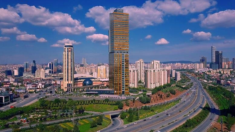 Exterior view of the towering glass-facade Palladium Tower under a blue sky.