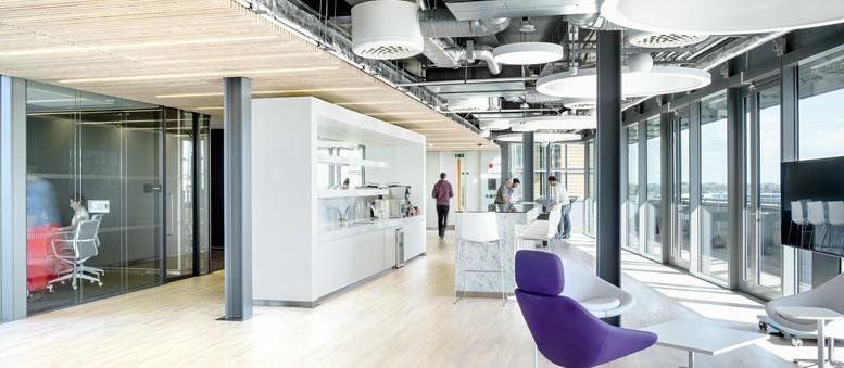 Spacious open-plan lounge area with purple chairs and floor-to-ceiling windows at Point Square Offices.