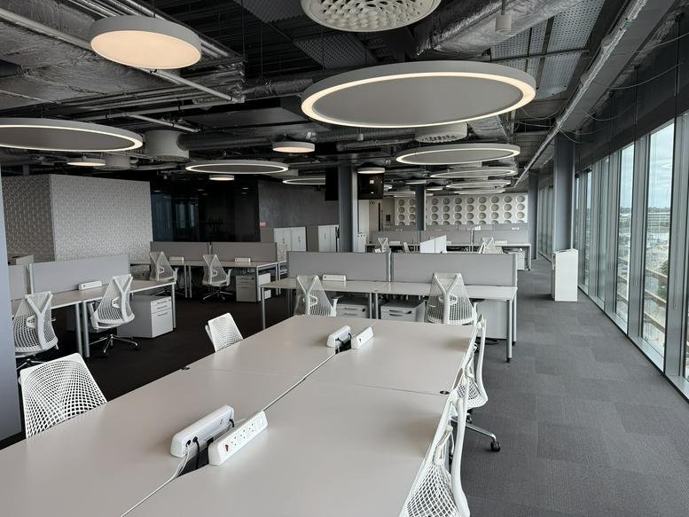 Spacious open-plan workspace at Point Village with modern white desks and circular overhead lighting.