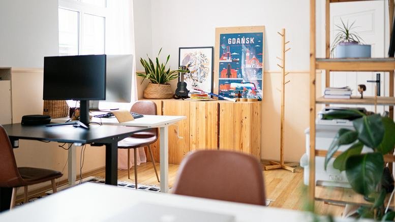 Spacious communal office area with wooden cabinetry, multiple workstations, and indoor greenery.
