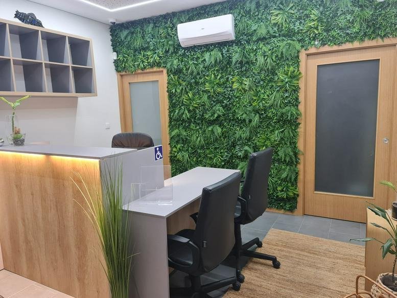 Reception area at Praceta Carlos Capítulo, Nº 6 A, Loja Esq. featuring a green plant wall and wooden desk.