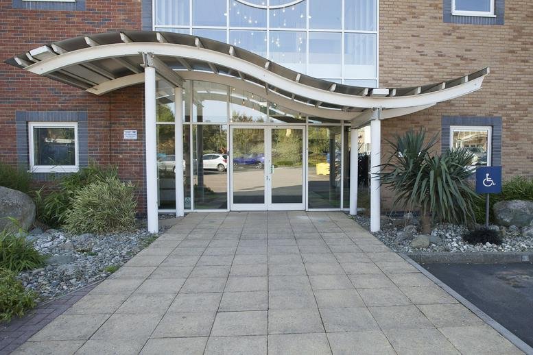 Exterior entrance of Relay Point, Green Lane, featuring a modern wave-shaped canopy and glass facade.