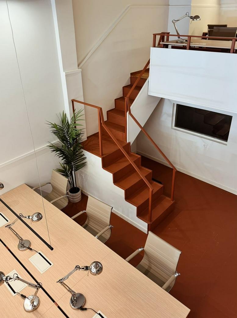 Mezzanine office at Rua Brito e Cunha,27 with wood stairs and long desks.