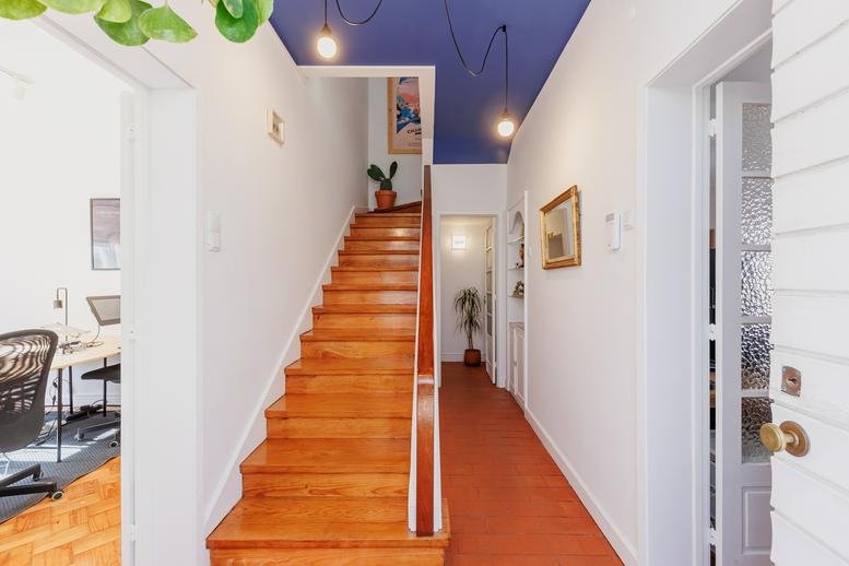 Entrance hallway at Rua de Nossa Senhora de Fátima 43 with wooden stairs and blue ceiling.