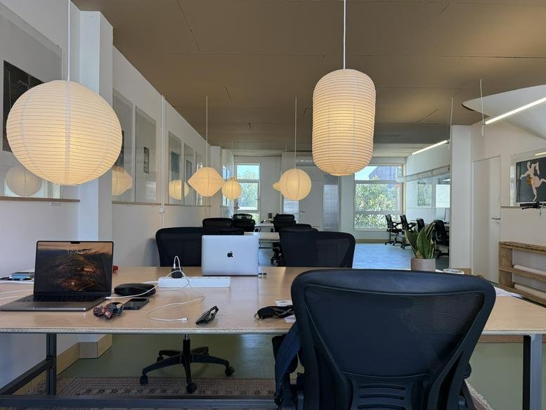 Spacious open-plan workspace at Rua do Almirante Leote do Rego, 204 with warm globe lighting and modern desks.