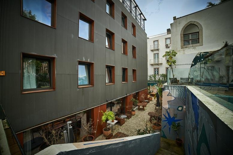 Exterior view of the dark modern facade of the building at Rua Fernandes Tomás 64 with a central courtyard.