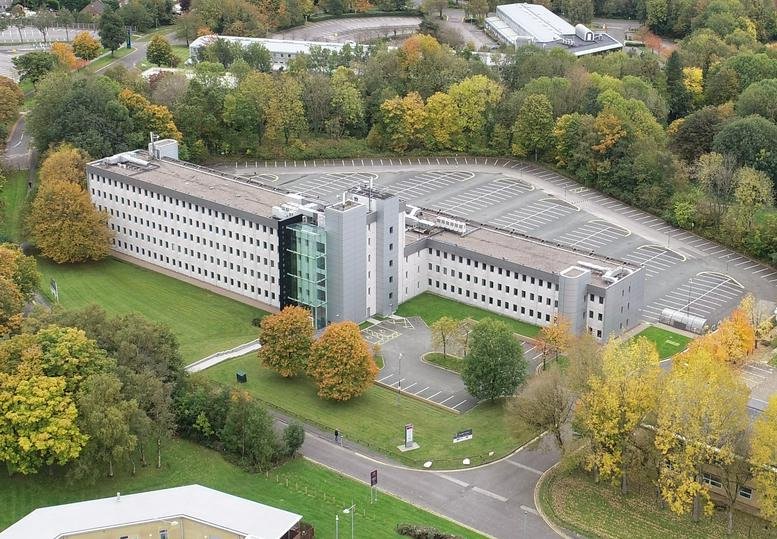 Aerial view of Rutherford House, Warrington Road, featuring a large multi-story office building with ample parking.