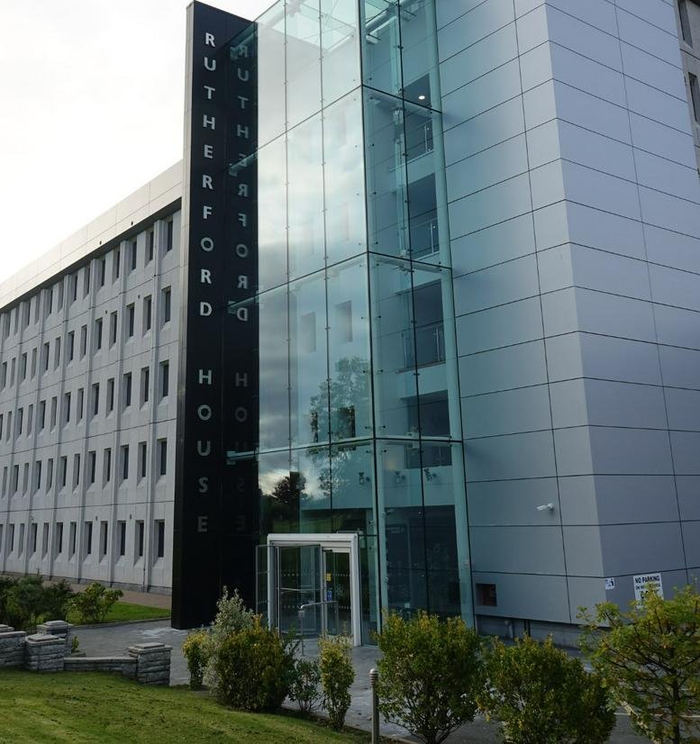 Modern glass entrance of the building facade with prominent black signage.