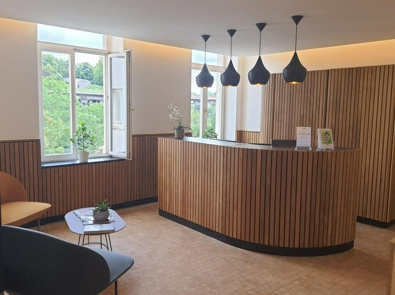 Modern reception area with a curved wooden slat desk and stylish black pendant lighting.