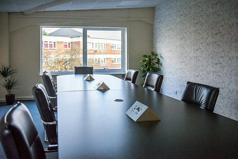 Spacious boardroom at 1 Alvin Street, Gloucester featuring a large dark wood table and black leather chairs.