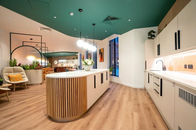 Modern communal kitchen and breakout space at 1 Balloon Street Manchester featuring a teal ceiling.