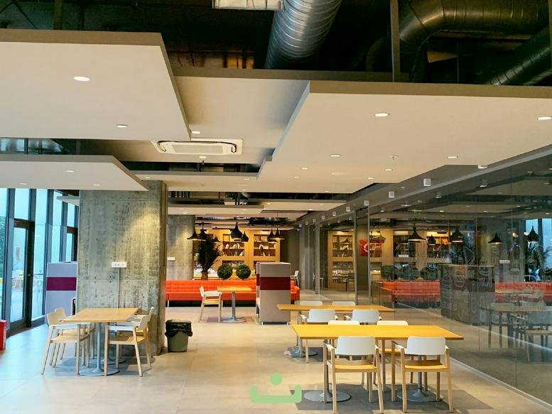 Spacious open-plan cafeteria area with wooden tables and orange accent seating.