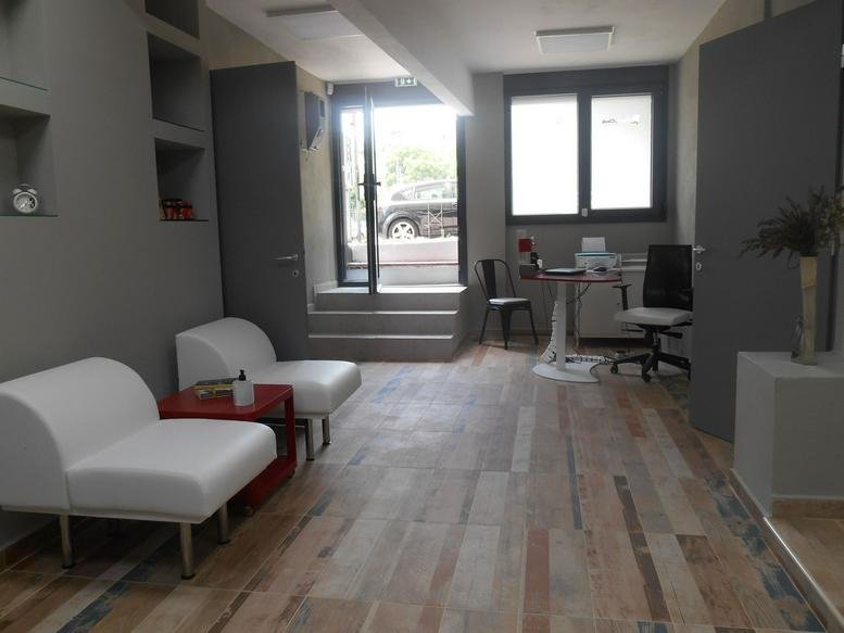Reception and lounge area at 1 Kassandrou street featuring white armchairs and wooden flooring.
