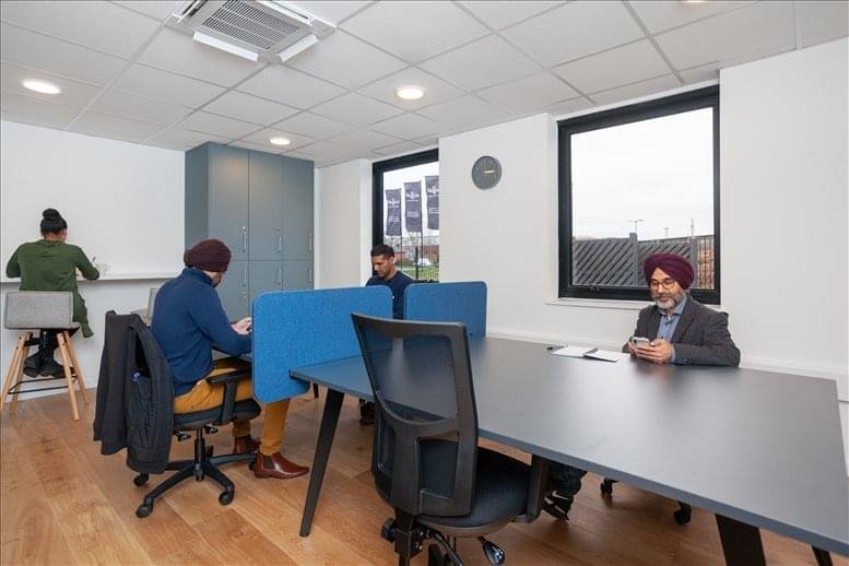 Collaborative workspace with people working at a grey table with blue privacy dividers.