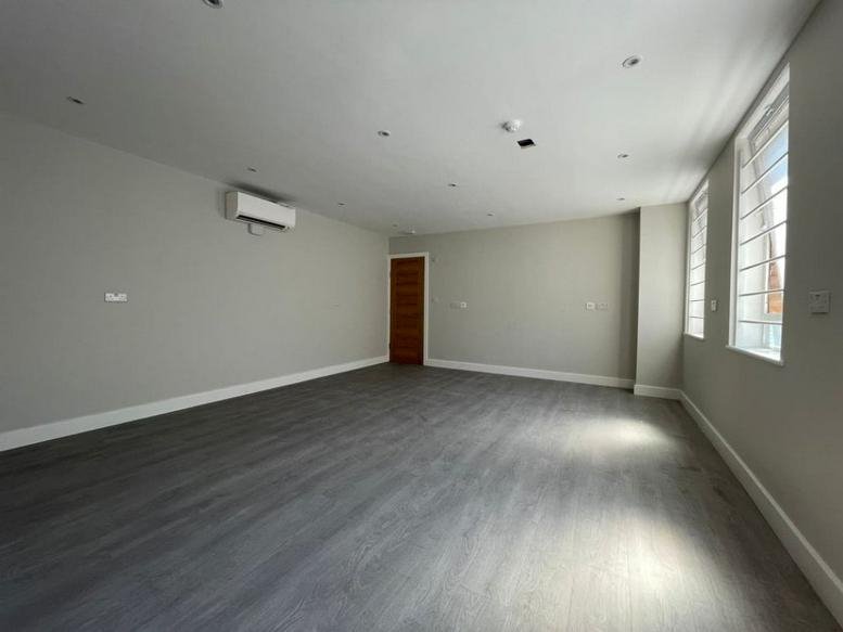 Spacious open-plan office with grey flooring and natural light at 1 Norman Road, London, N15