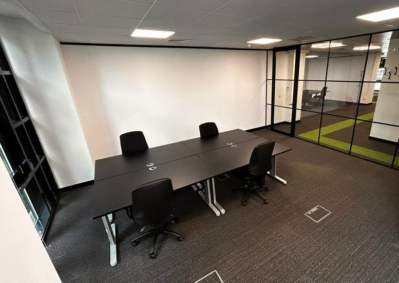 Professional six-person meeting room featuring a black boardroom table and glass walls.