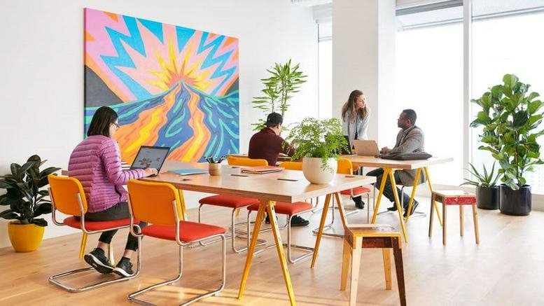 Bright, open-plan workspace with a large sunburst mural and vibrant orange chairs at 1 St Peter's Square.
