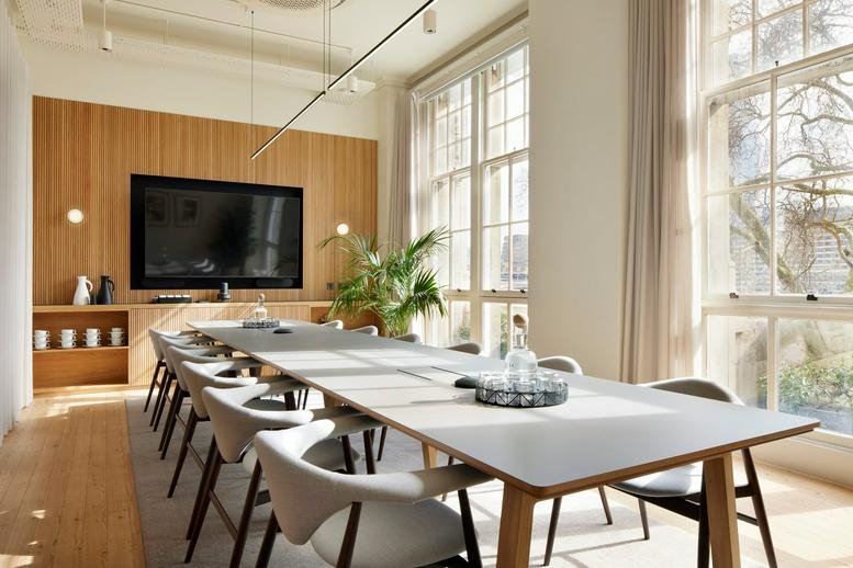 A light-filled meeting room at 1 Temple Avenue featuring a long table and wooden wall paneling.