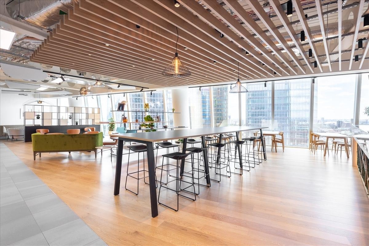 Spacious communal lounge with warm wood slat ceilings, high tables, and floor-to-ceiling city views.