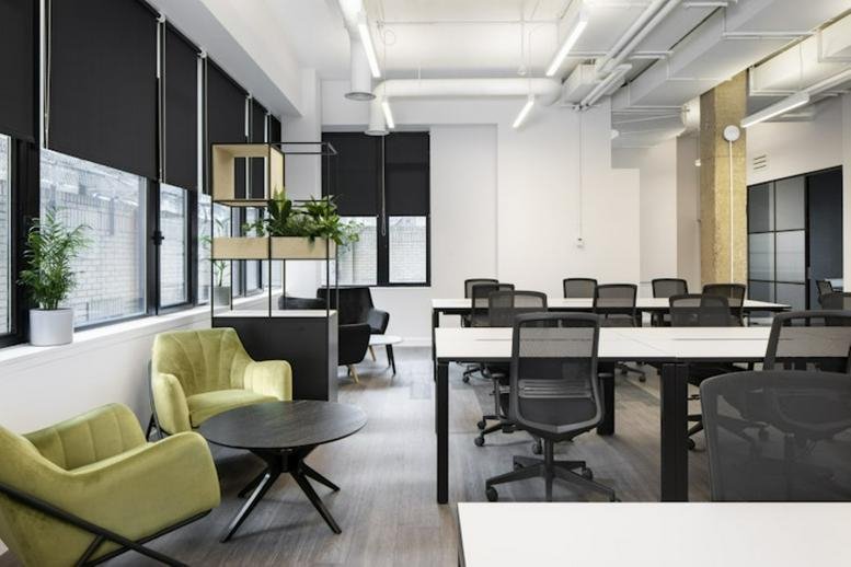 Lounge area with lime green armchairs and a circular coffee table in an open-plan office at 100 Bunhill Row.