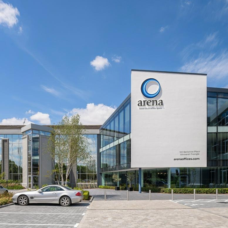 Modern glass and steel exterior facade of 100 Berkshire Place, Winnersh with a white branded feature wall.