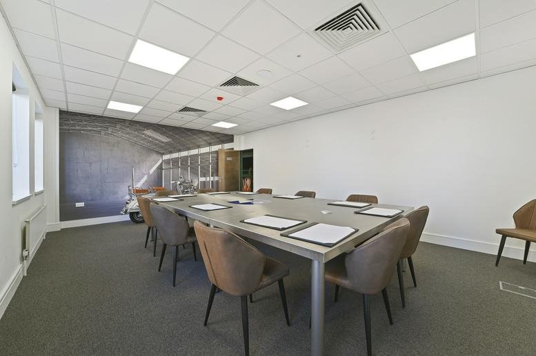Professional boardroom with a long table, brown leather chairs, and a large wall mural.