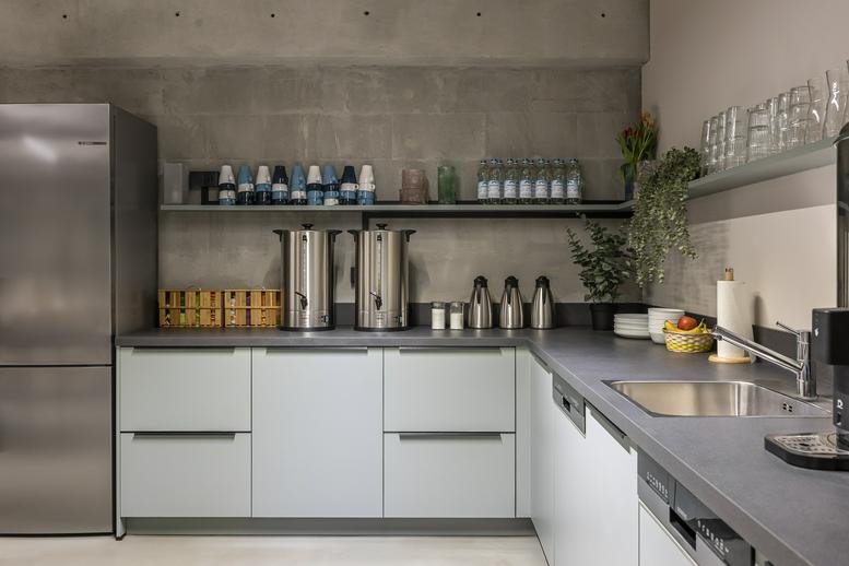 Sleek communal kitchen with grey cabinetry and stainless steel appliances.