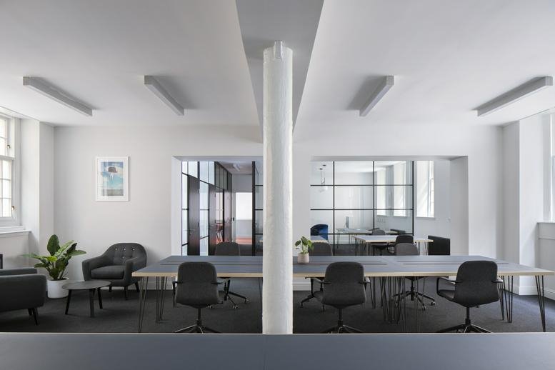 Spacious communal coworking area at 106 Hope Street with grey seating and large windows.