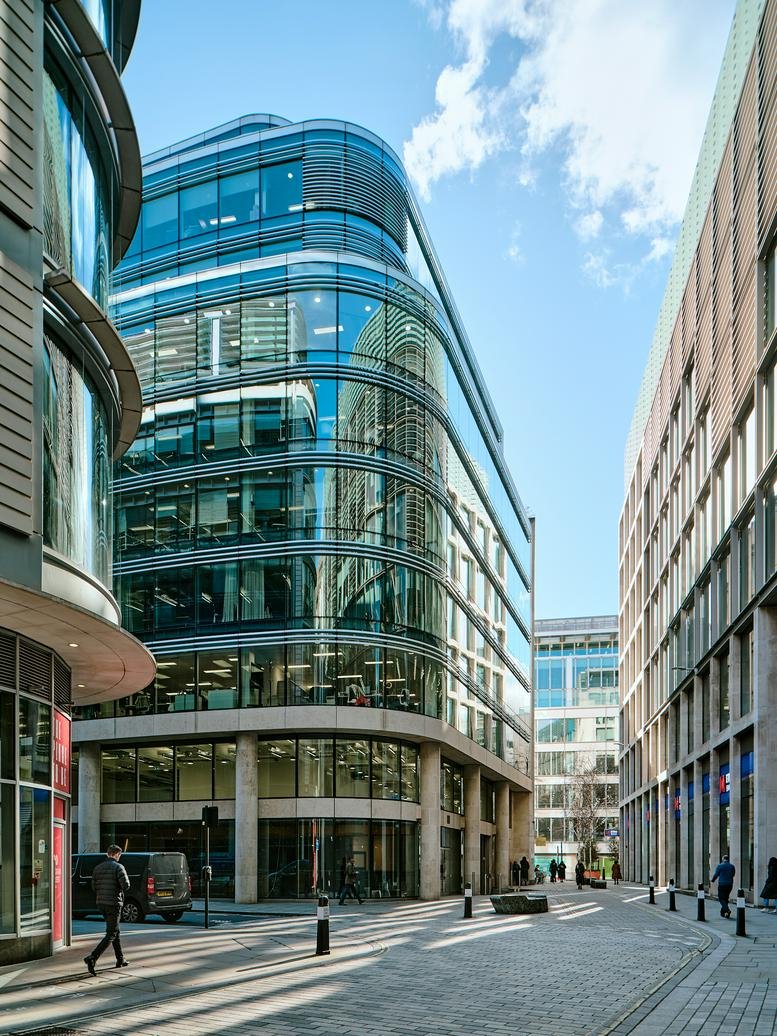 Corner view of the modern glass and stone building facade against a blue sky.