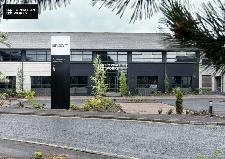 Modern exterior of 11-12 Edgewater Road at Edgewater Business Park with dark gray facade and large signage.