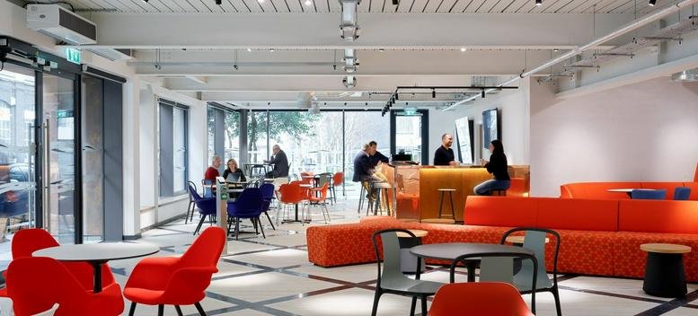 Spacious communal lounge with orange seating and a café area at 11 Burford Road, Stratford.