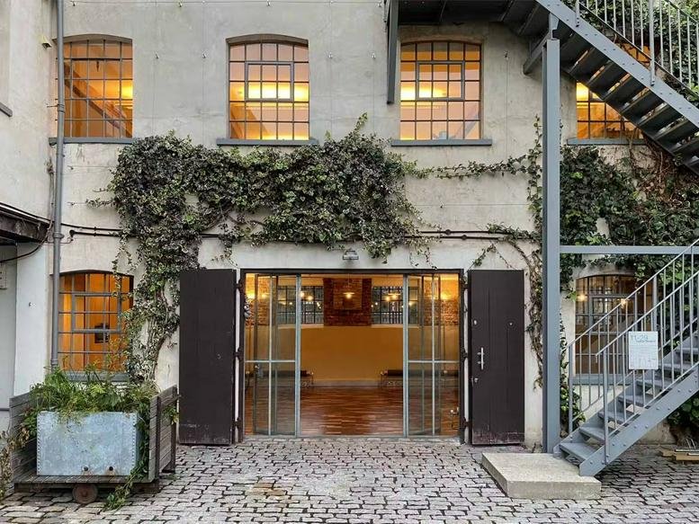 Exterior of the industrial brick building at 11, Fashion Street with climbing ivy and an external steel staircase.