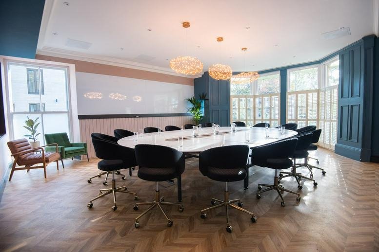 Conference room featuring a marble-topped oval table and blue paneled walls.