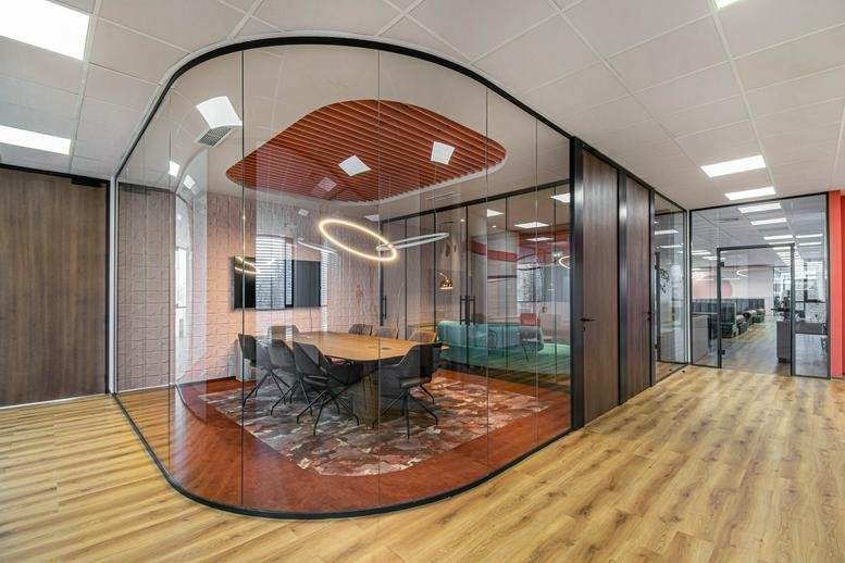 A modern curved glass meeting room at 111 Boulevard Tsarigradsko shose with a circular halo light and wooden table.