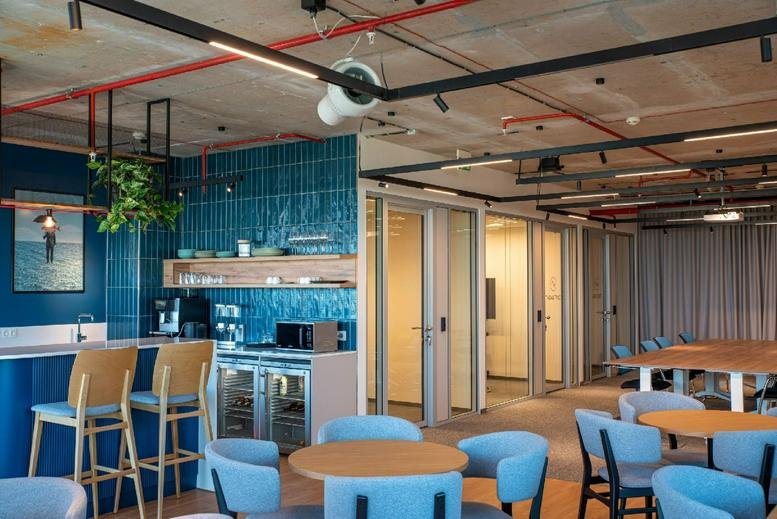 Spacious communal lounge at 115G Tsarigradsko Shose, Megapark, Sofia with blue tiled walls and wooden cafe seating.