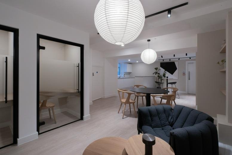 Spacious breakout lounge with globe pendant lights, velvet sofa, and dining tables.