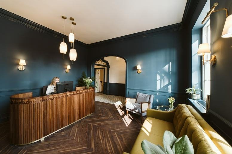 Elegant reception area at 12-18 Theobalds Road featuring a fluted wood desk and dark teal walls.